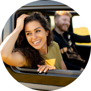 A couple rides in a car on a sunny day