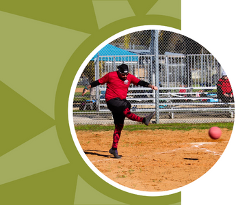 A man kicks a ball while playing kickball.