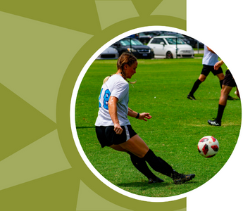 A woman kicks a soccer ball.